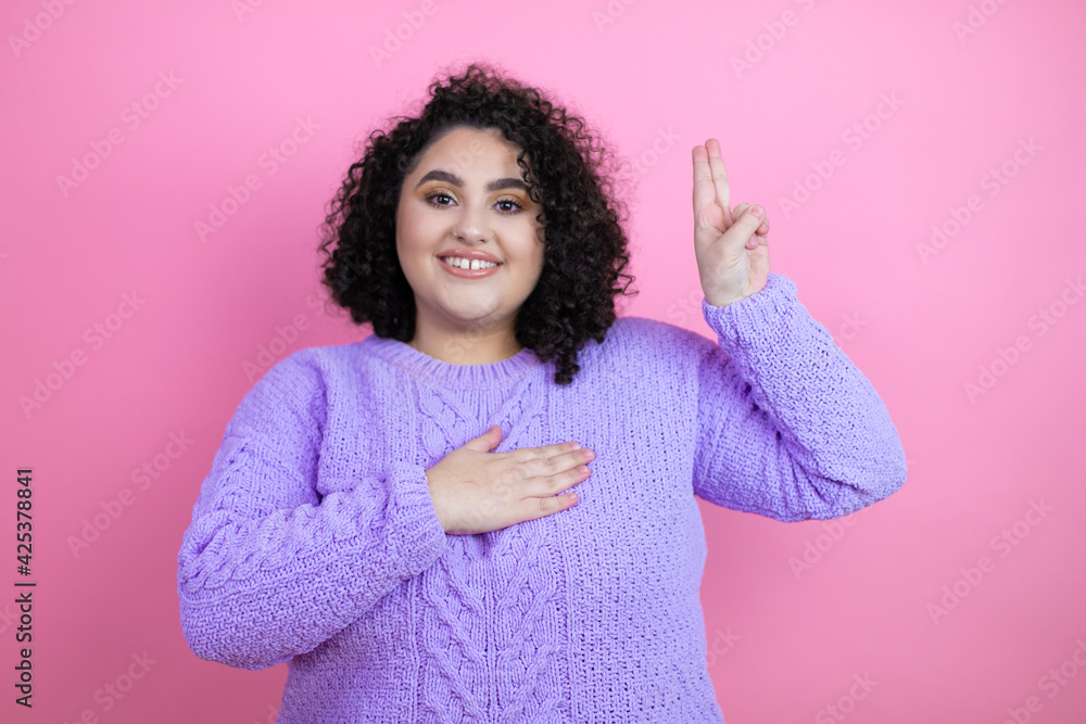 Young beautiful woman wearing casual sweater over isolated pink background smiling swearing with hand on chest and fingers up, making a loyalty promise oath Young beautiful woman wearing casual sweater over isolated pink background smiling swearing with hand on chest and fingers up, making a loyalty promise oath