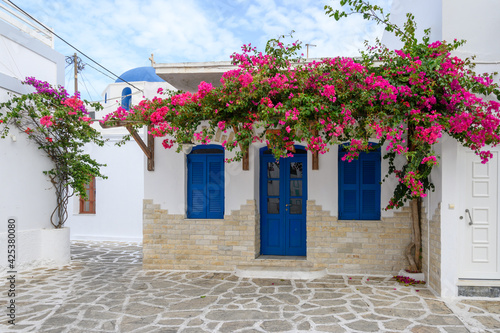 Greek house with blue doors and decorated with bougainvillea flowers on Antiparos island. Cyclades, Greece