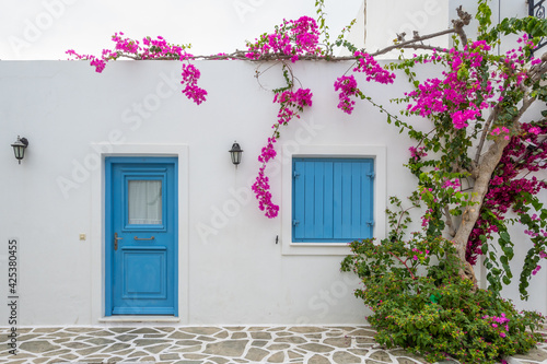 Fototapeta Naklejka Na Ścianę i Meble -  Greek house with blue doors and decorated with bougainvillea flowers on Antiparos island. Cyclades, Greece