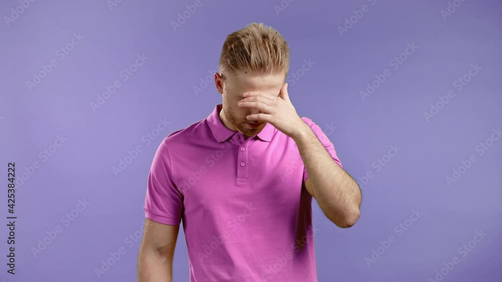 Portrait of young man doing facepalm gesture, like no, I forgot. Unhappy guy in pink wear feeling sorrow, regret, drama, failure. He isolated on violet wall Portrait of young man doing facepalm gesture, like no, I forgot. Unhappy guy in pink wear feeling sorrow, regret, drama, failure. He isolated on violet wall