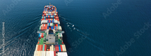 Aerial drone ultra wide photo of huge container ship cruising deep blue open ocean sea near logistics container terminal port photo