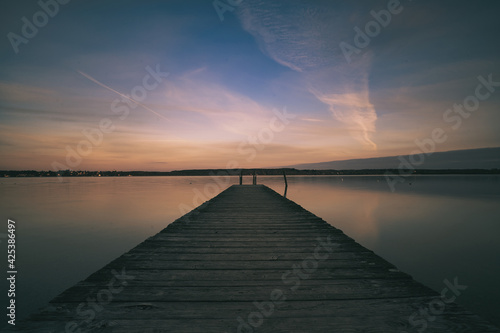 Fototapeta Naklejka Na Ścianę i Meble -  Early sunrise with clouds and pier on the lake