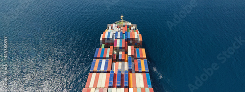 Aerial drone ultra wide photo of huge container ship cruising deep blue open ocean sea near logistics container terminal port