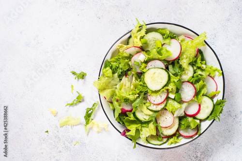 Green salad with fresh leaves, radish, cucumber and ollive oil.