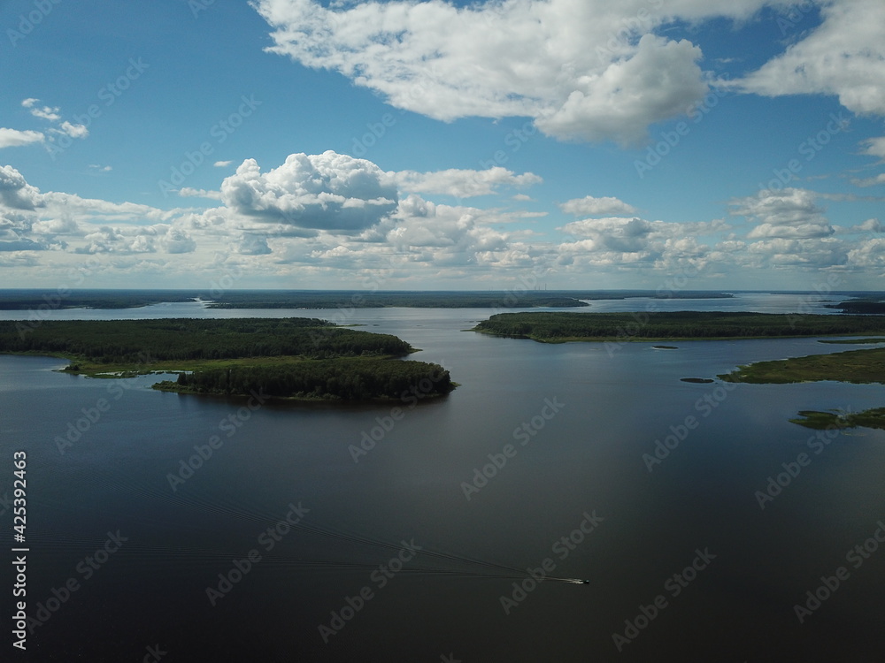 Beautiful river landscape top view from drone. Green small islands against a background of blue sky and white clouds