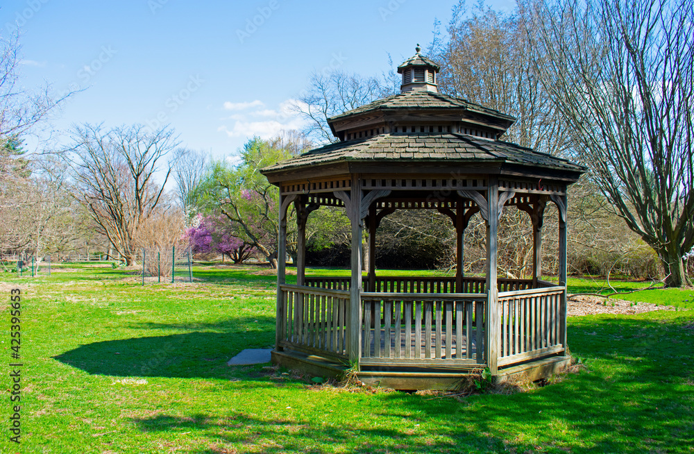 Wooden gazebo at Rutgers Gardens against a background of new plant growth on a sunny day in Springtime  -02