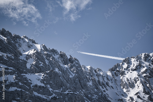 snow covered mountains with plane in the sky