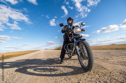  man in a black uniform on bike against the backdrop of panorama of field and blue sky. motorcycle travel concept © hiv360