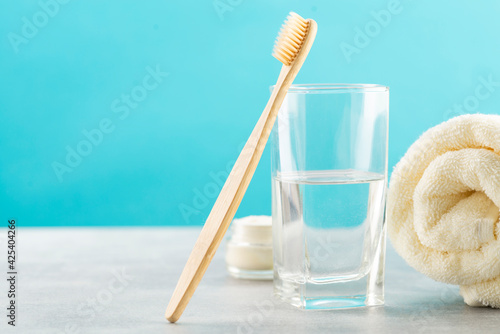 A bamboo toothbrush, a glass of water, a white cotton towel and toothbrush powder in a jar. Biodegradable personal care products. No plastic concept