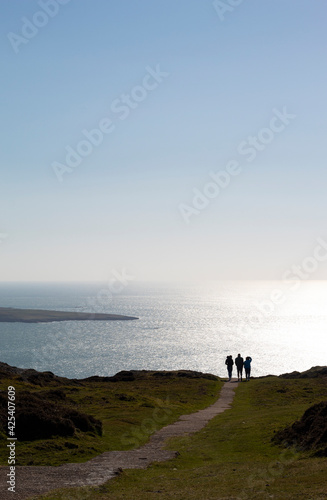 Wales, remote dramatic Bardsey island. Isolated remote landscape with foreground of green fields and the calm sea with sun glinting, in the distance. Medieval pilgrimage destination. Copy space.