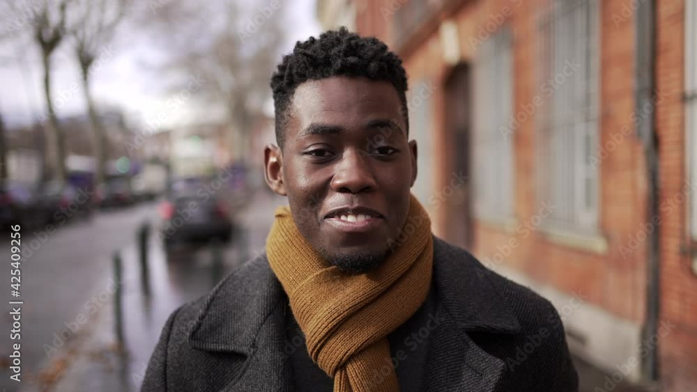 Charismatic happy black African man walking in city downtown smiling at camera during winter season Charismatic happy black African man walking in city downtown smiling at camera during winter season