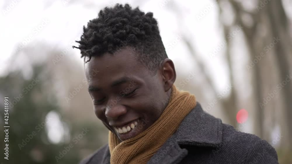 Charismatic happy black African young man smiling outside wearing scarf and winter coat Charismatic happy black African young man smiling outside wearing scarf and winter coat