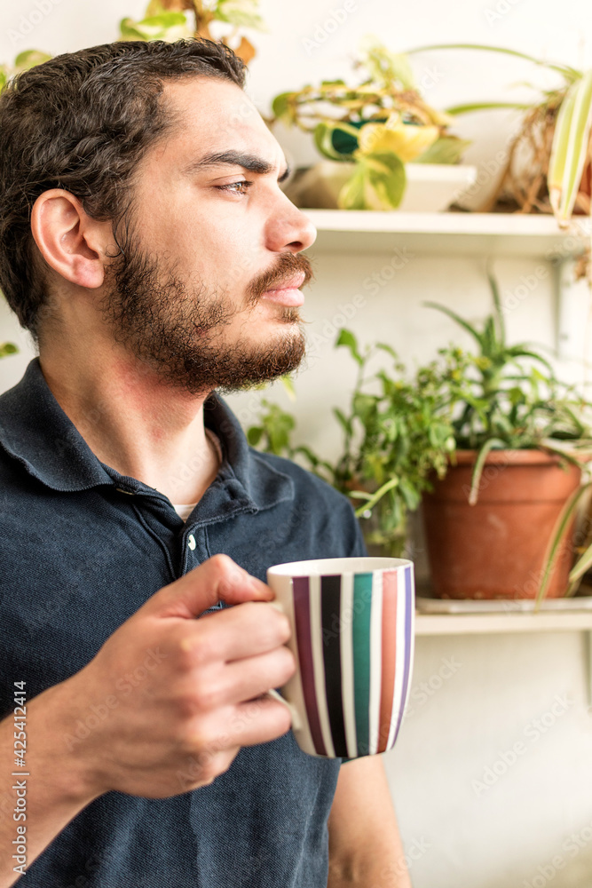 Serious young man with cup of coffee, standing on the balcony. Serious young man with cup of coffee, standing on the balcony.