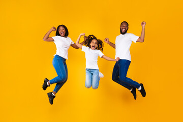 Portrait of emotional black family jumping at studio