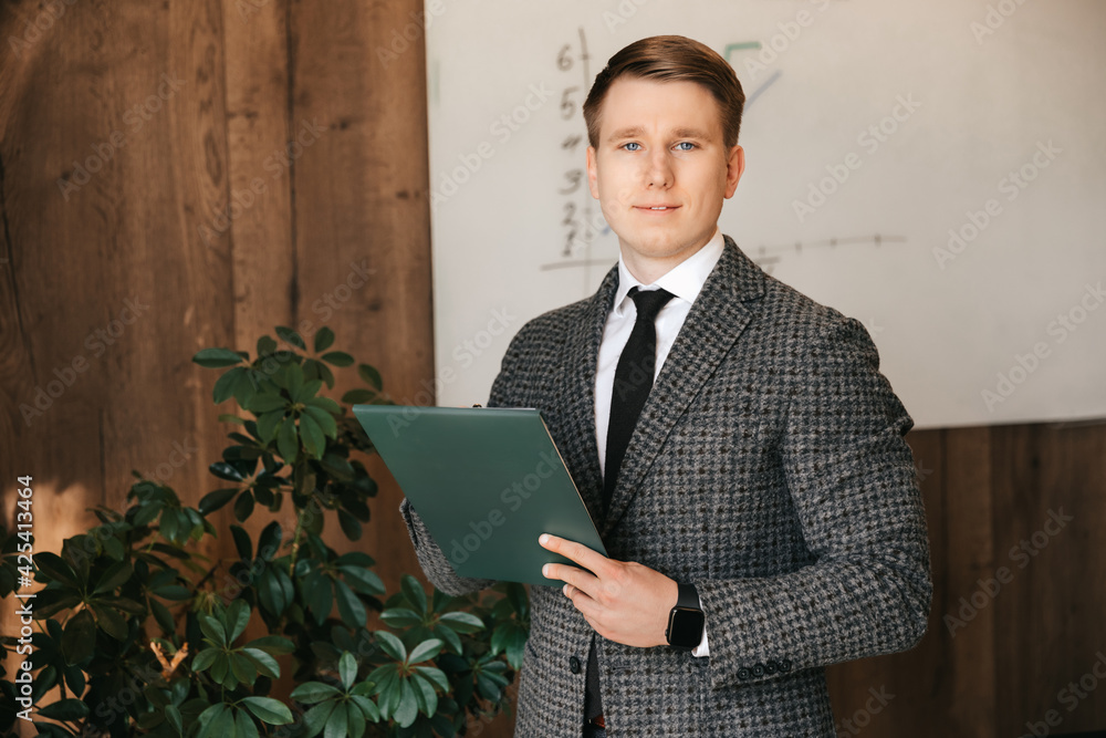 Businessman man in his office stands with documents and a pen in his hands, office worker. A man in a classic suit. Businessman man in his office stands with documents and a pen in his hands, office worker. A man in a classic suit.