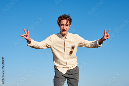 A Caucasian man from Spain making victory signs with both hands on clear sky background