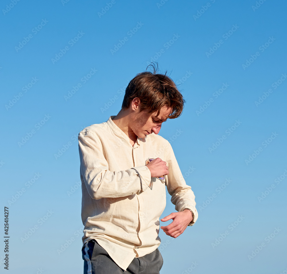A Caucasian man wearing a beige shirt from Spain hanging his glasses from his chest pocket on clear sky background A Caucasian man wearing a beige shirt from Spain hanging his glasses from his chest pocket on clear sky background
