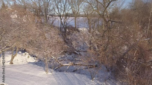 Aerial view liftin up from behind the trees, and showing the surrounding fields covered of snow. photo