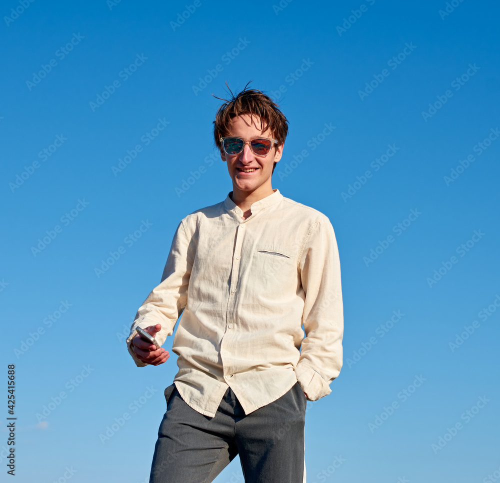 A Caucasian man wearing a beige shirt from Spain standing with hands in his pockets on sky background A Caucasian man wearing a beige shirt from Spain standing with hands in his pockets on sky background