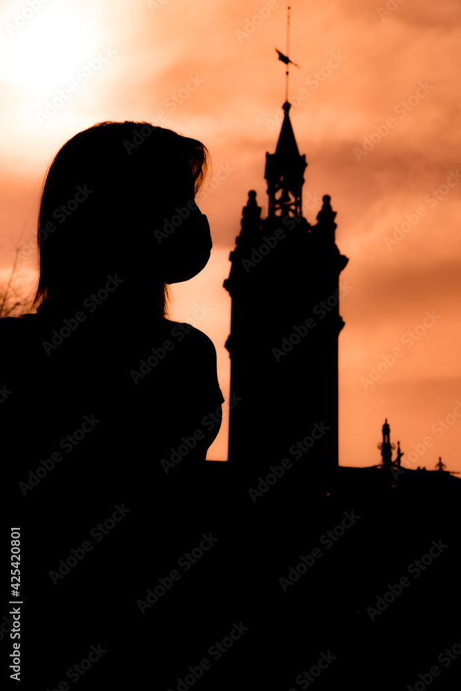 Silhouette of a woman with a mask and a tower with a weather vane on top