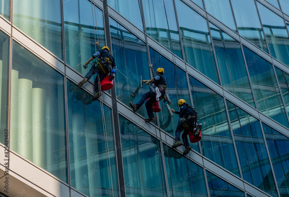 skilled glass cleaners who lower themselves with slings from above