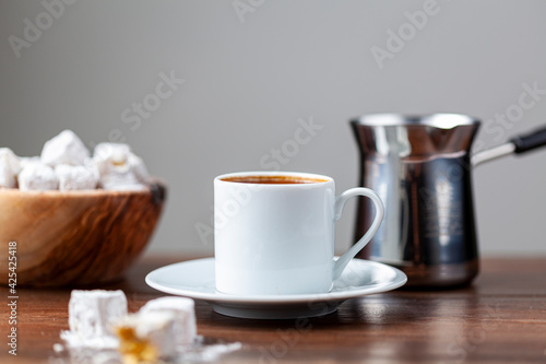 Traditional Turkish coffee served in classical cups with Turkish delights. A metal coffee pot is in the background. photo