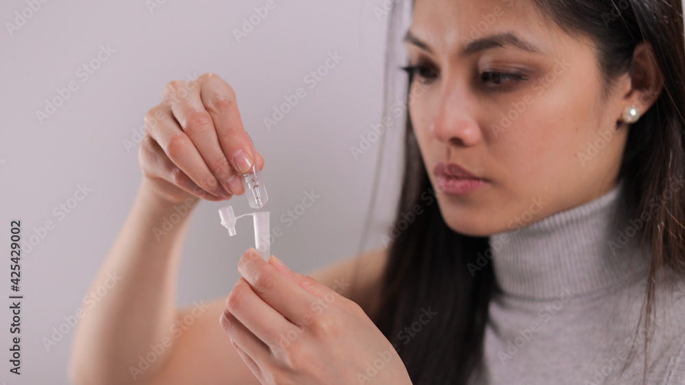 Young woman performs a Covid-19 antigen self-test - studio photography Young woman performs a Covid-19 antigen self-test - studio photography