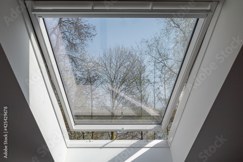 Photography Close up view at slightly opening white Tilt Window Skylights  at attic and defocused of outdoor tree in winter