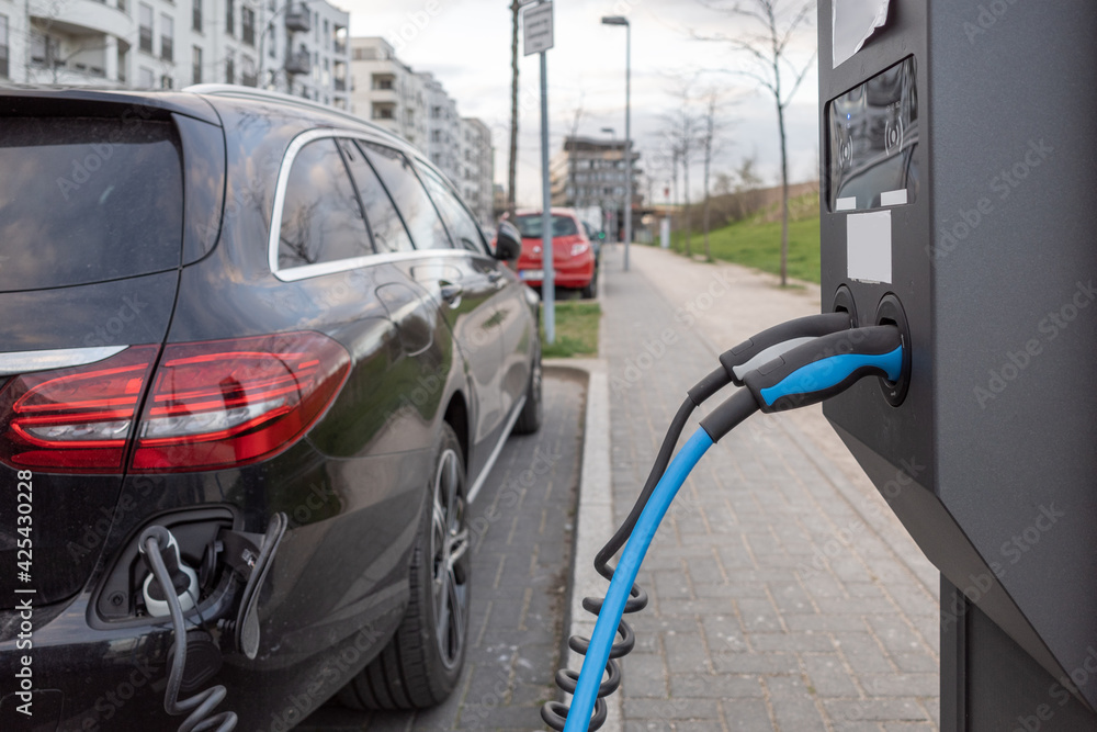 Selective focus, EV Electric Vehicle changing station on sidewalk beside car park on street in Germany.
