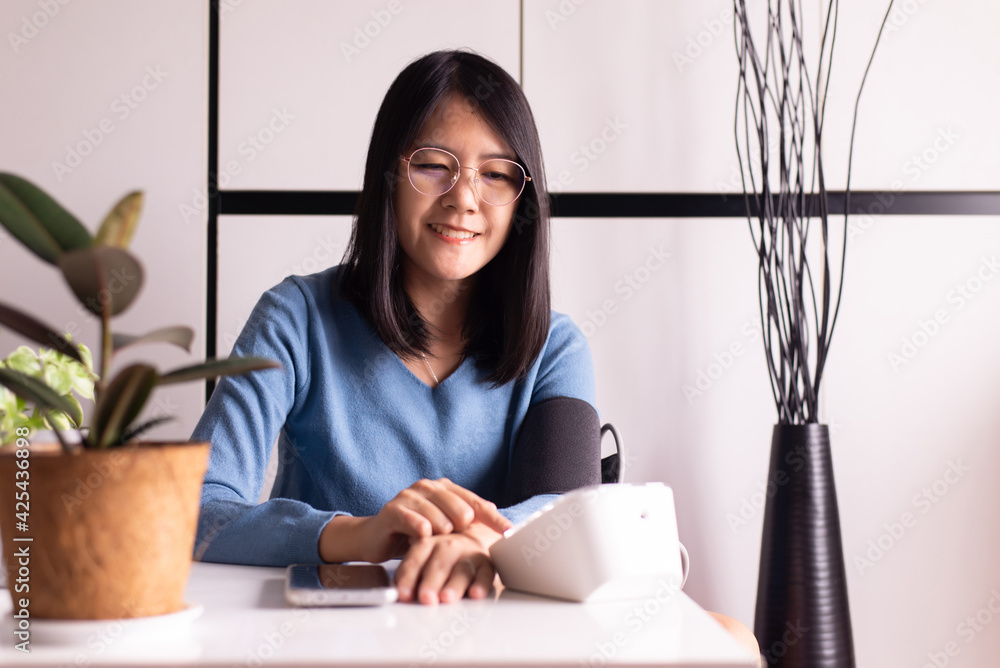 Happy asian woman using blood pressure & heart rate monitors in yourself at home Happy asian woman using blood pressure & heart rate monitors in yourself at home