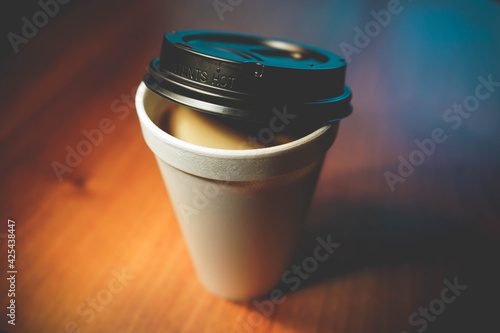 Styrofoam coffee cup with lid on wood table