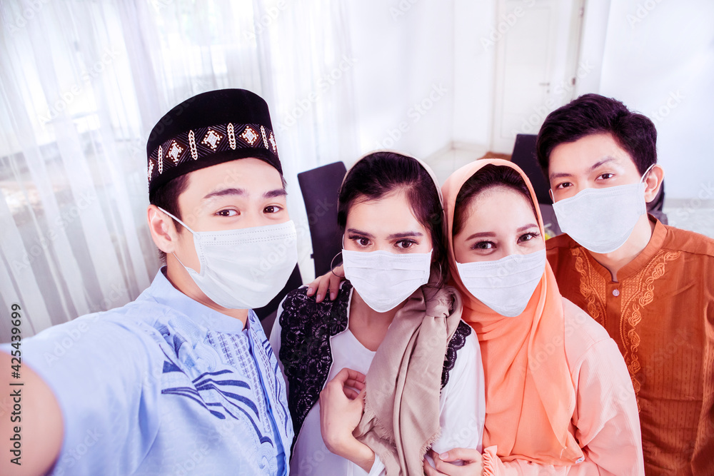 Four Muslim people in mask taking selfie at home