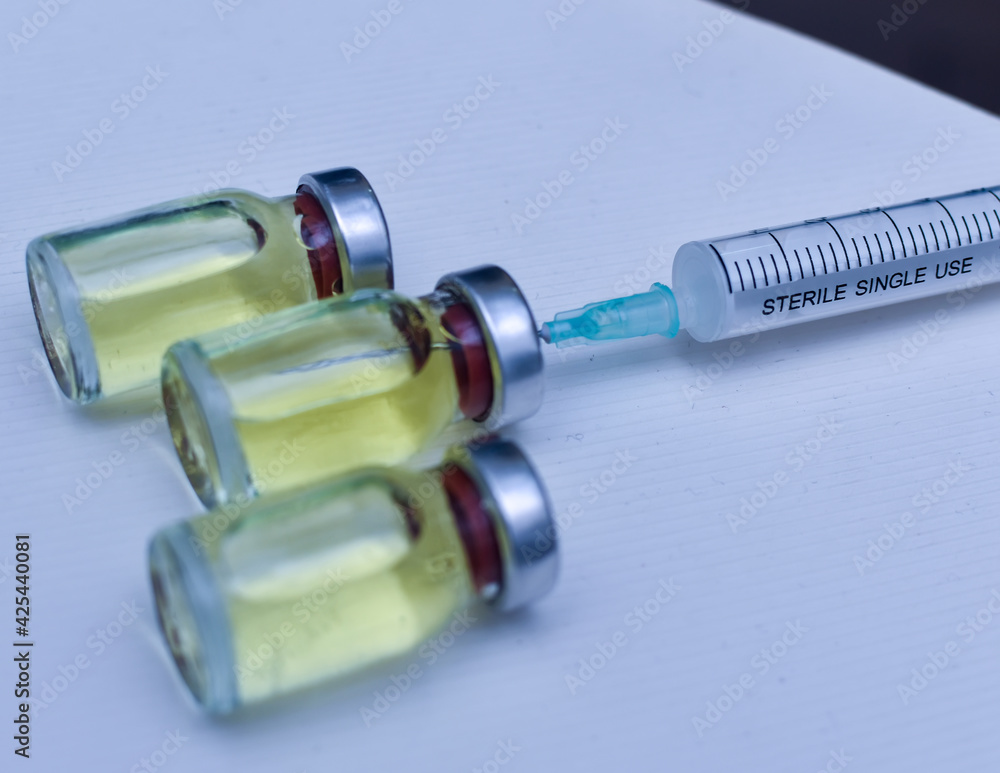 Vial of drugs injection or vaccine with syringe needle on a white background for cure and prevention of sickness Vial of drugs injection or vaccine with syringe needle on a white background for cure and prevention of sickness