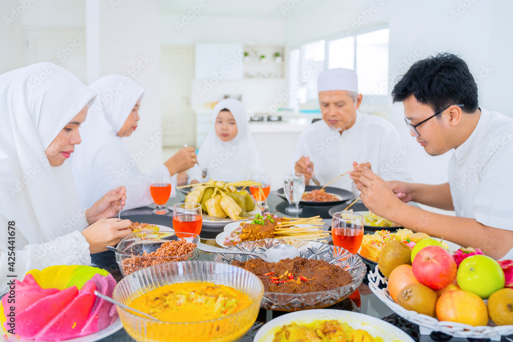 Muslim little girl having dinner with her family