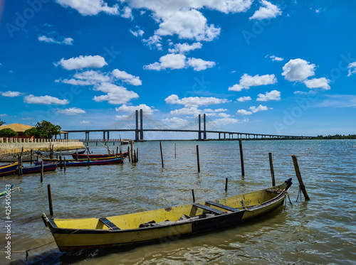 Barcos de pesca a remo e uma ponte longa ao fundo