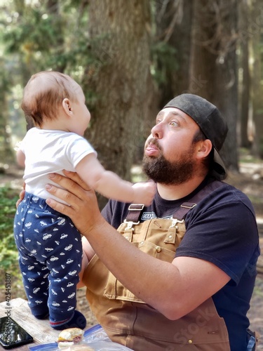 A new father makes a funny face that has his baby son giggling. 