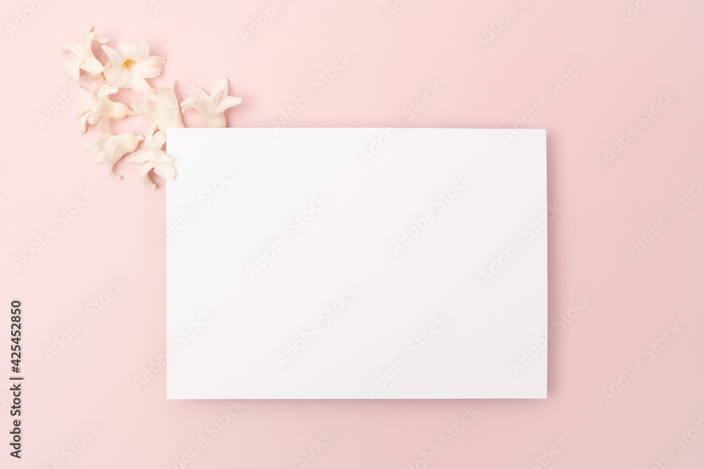 White blank stationery flat lay with hyacinth on pink background