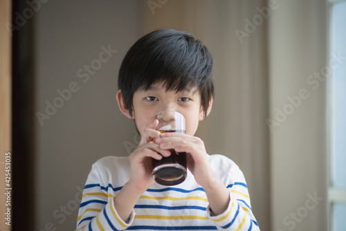 Little asian boy drinking soft drink coca cola soda