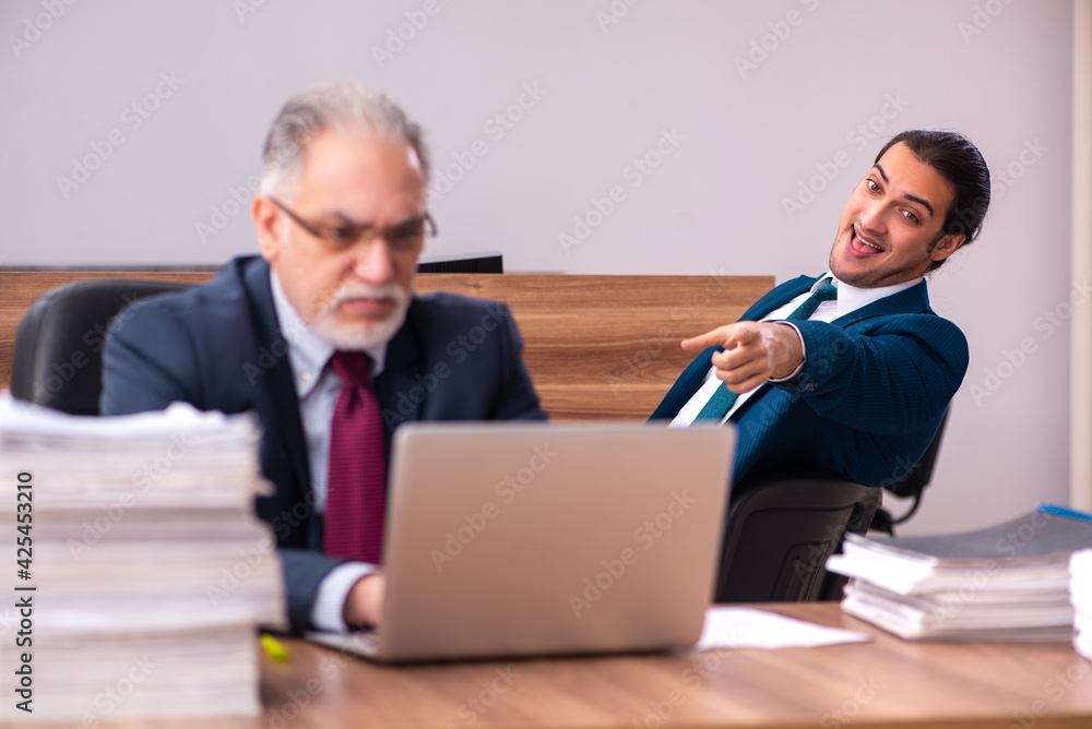 Old male employer and young male assistant in bullying concept Old male employer and young male assistant in bullying concept