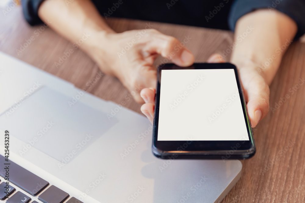 Top view female hands holding smart phone with blank white screen. Women hands workspace, close-up hand holding smartphone blank screen for text and content on wood table background.