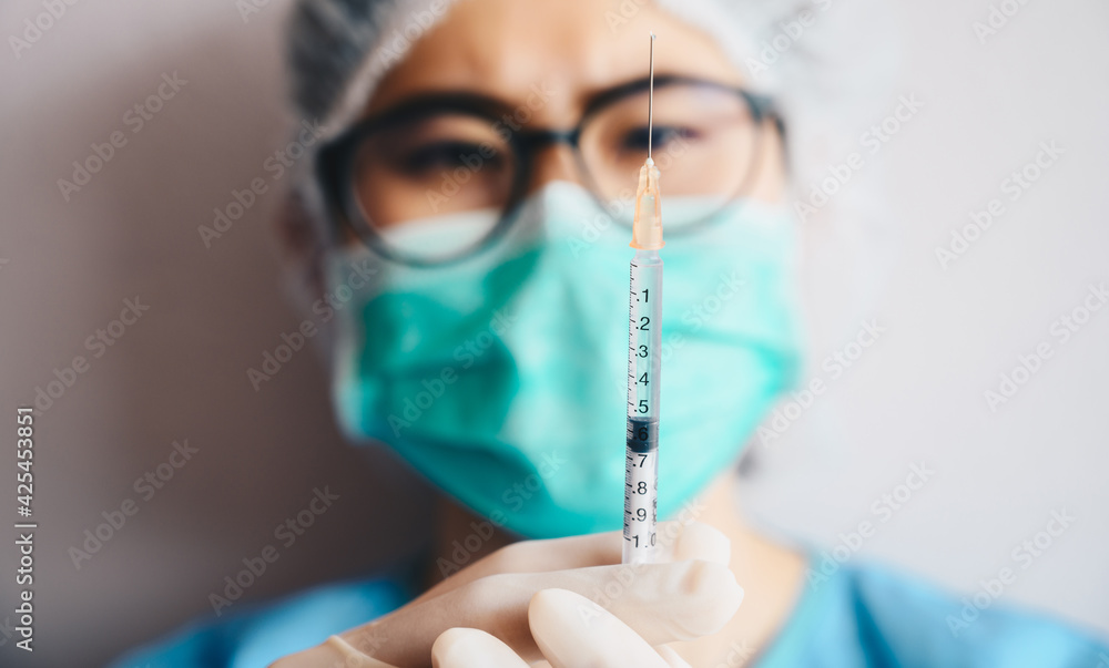 Headshot of Healthcare worker looking a syringe that contain covid-19 vaccine before injection vaccine to patients. Headshot of Healthcare worker looking a syringe that contain covid-19 vaccine before injection vaccine to patients.