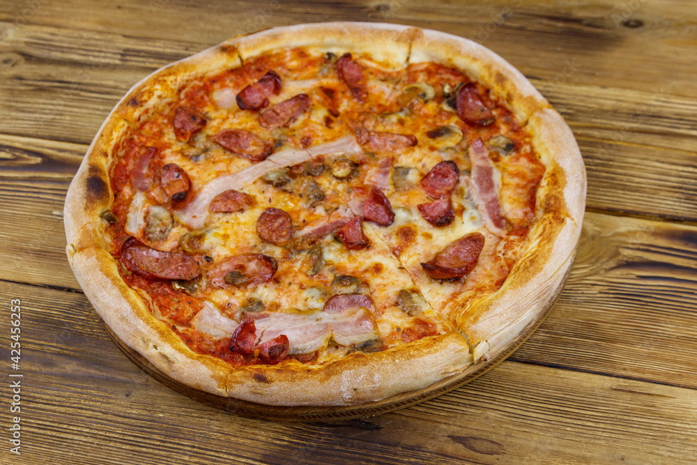 Delicious fresh pizza with sausage, mushrooms and cheese on a wooden table