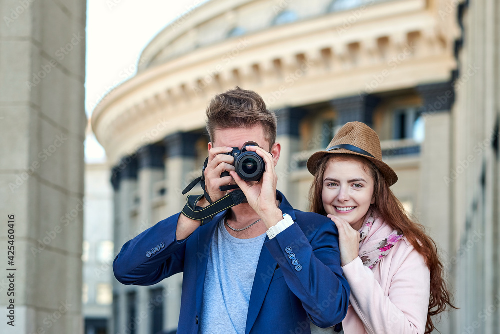 Happy love couple of tourists taking photo on excursion or city tour. Photos on the background of urban architecture