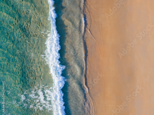 Aerial view nature summer sea waves in top-down drone shot perspective. Crashing wave line in Phuket South of Thailand. Andaman sea with foamy white texture. © BUDDEE