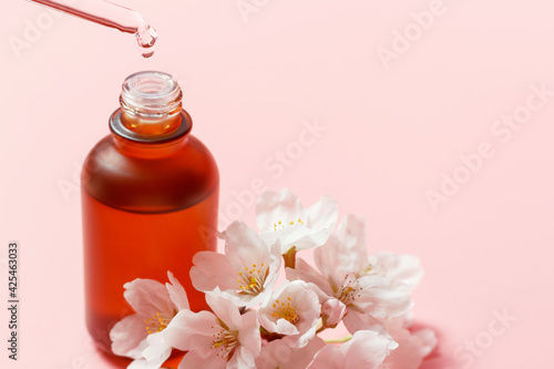 Bottle with serum and pipette on pink background close-up  copy space.