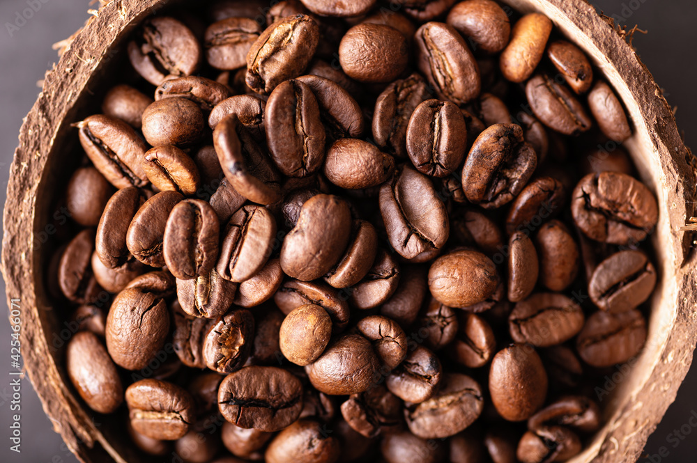 Naklejka premium black coffee beans arabica, aromatic in a coconut bowl, close-up