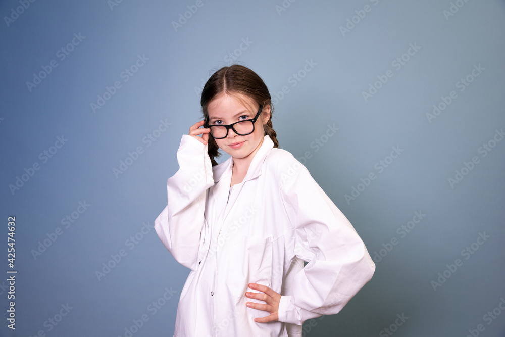 pretty young girl with black glasses and white work lab coat iis posing in front of blue background
