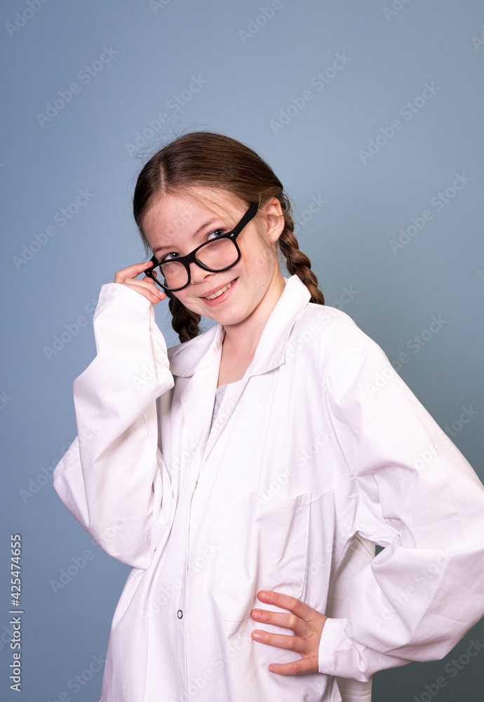 pretty young girl with black glasses and white work lab coat iis posing in front of blue background pretty young girl with black glasses and white work lab coat iis posing in front of blue background