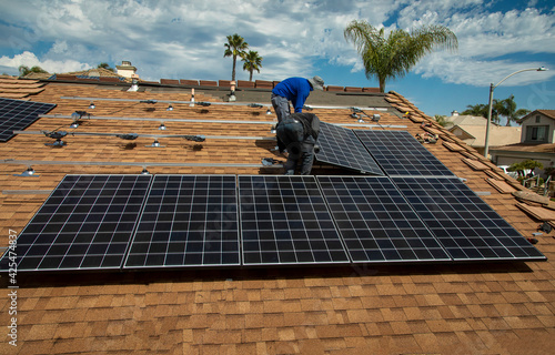 Workers installing solar panels on a tile roofon a sunny day photo