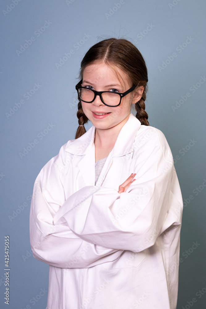 pretty young girl with black glasses and white work lab coat iis posing in front of blue background pretty young girl with black glasses and white work lab coat iis posing in front of blue background